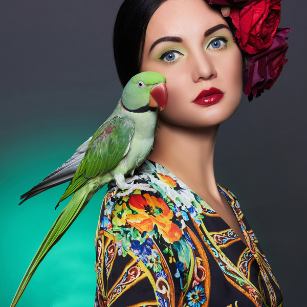 beautiful girl with a parrot and a flower in her hair.beauty young woman with colorful make-up and bird